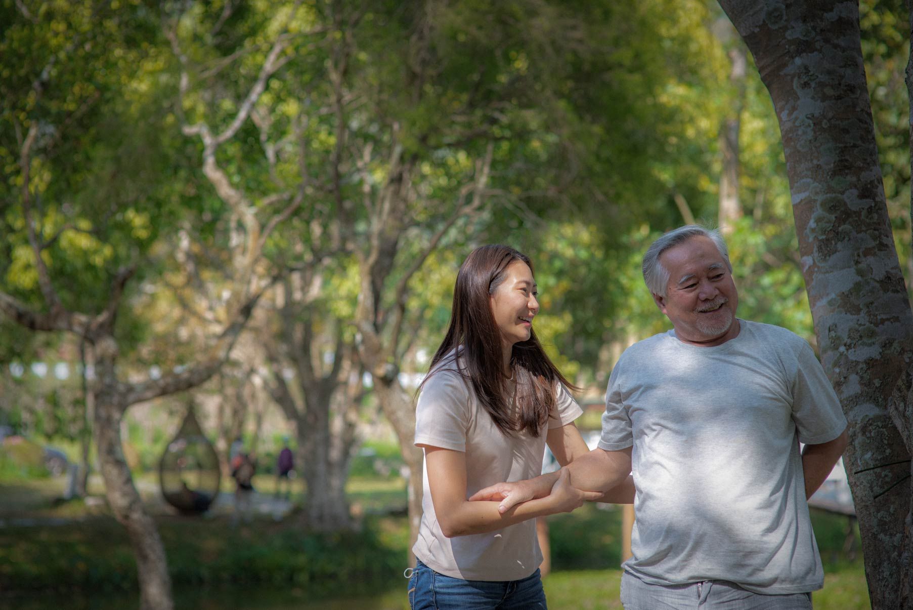 Older man and female partner walking in park